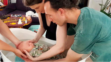 Parents donnant un bain sensoriel à leur nouveau-né pendant un atelier.