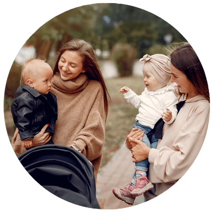 Deux mamans souriantes profitant d’une balade dans le parc avec leurs enfants, en pleine détente et partage.