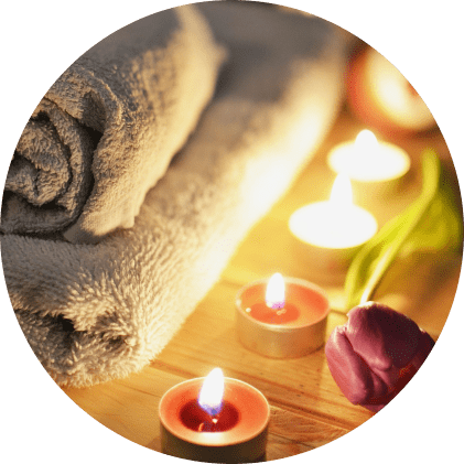 Image de bien-être : serviettes empilées, bougies allumées et tulipe posée à côté.